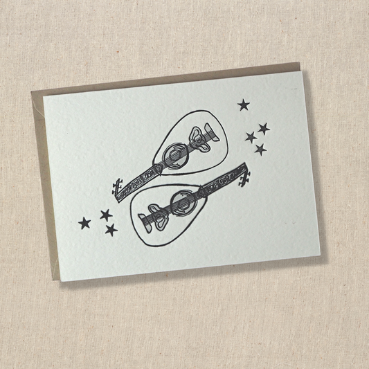 notecard with two out instruments with seven stars letterpress printed in black in on light cotton paper on top of a light kraft envelope.