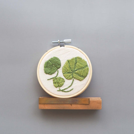 three nasturtium leaves embroidered on a natural linen fabric.
