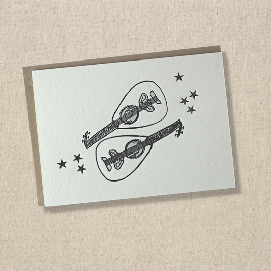 notecard with two out instruments with seven stars letterpress printed in black in on light cotton paper on top of a light kraft envelope. 