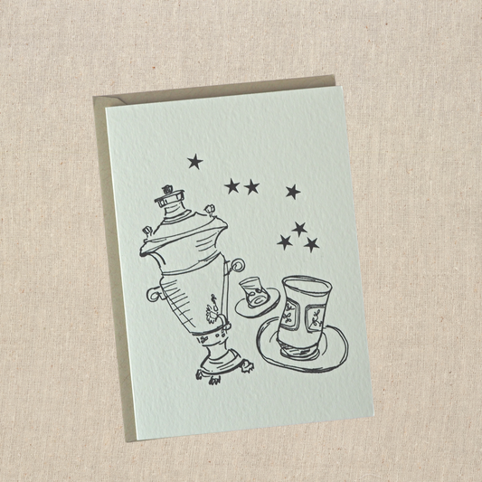 Greeting card with samovar , two tea glasses, and 7 stars letterpress printed in black ink on natural cotton paper  on top of a light kraft envelope 