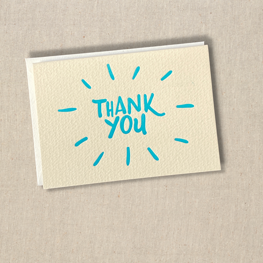 Greeting card that says thank you in turquoise ink with open starburst pattern around it.